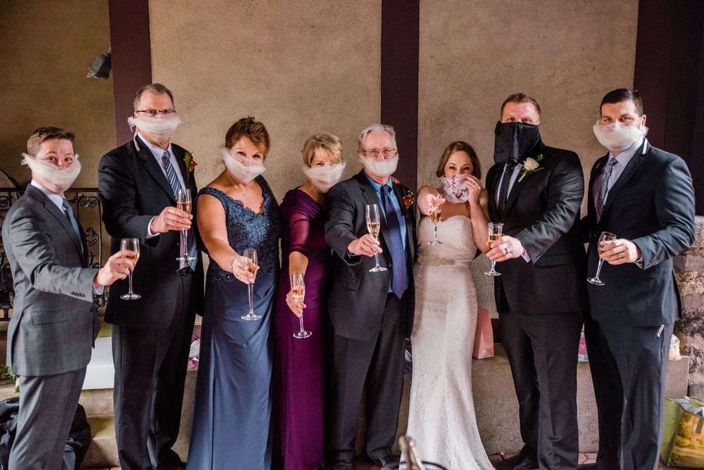 Wedding party wearing protective masks poses together for a formal group photo.