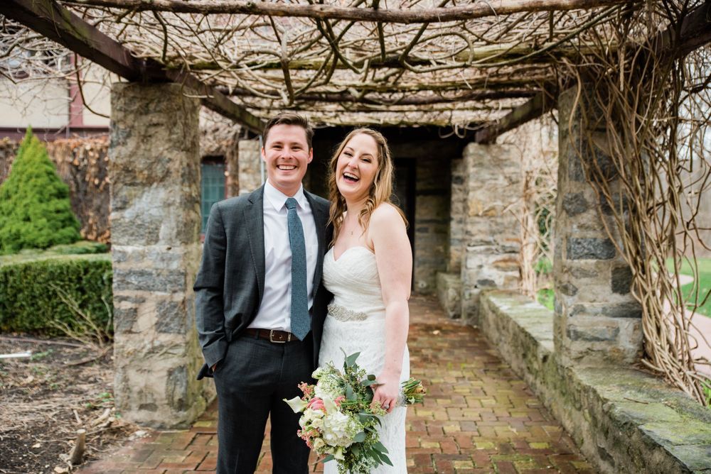 Newlyweds share a joyful moment together beneath rustic stone architecture and twisting vines.