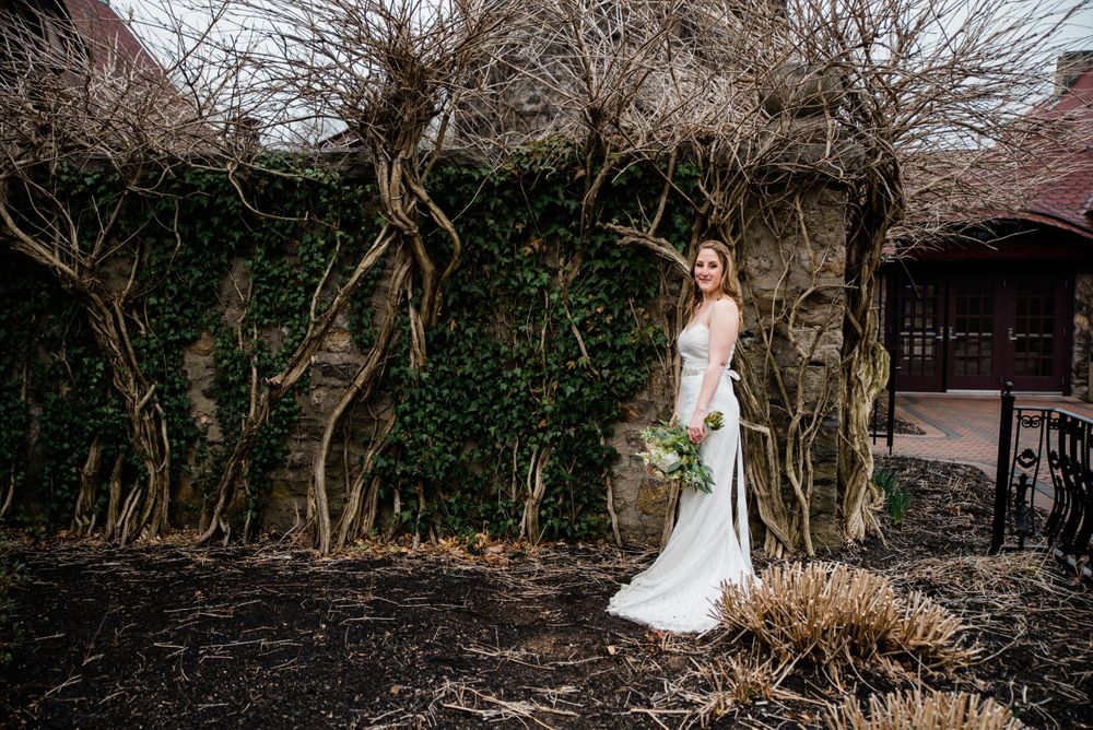 Elegant bridal portrait among bare winter vines and stone architecture.