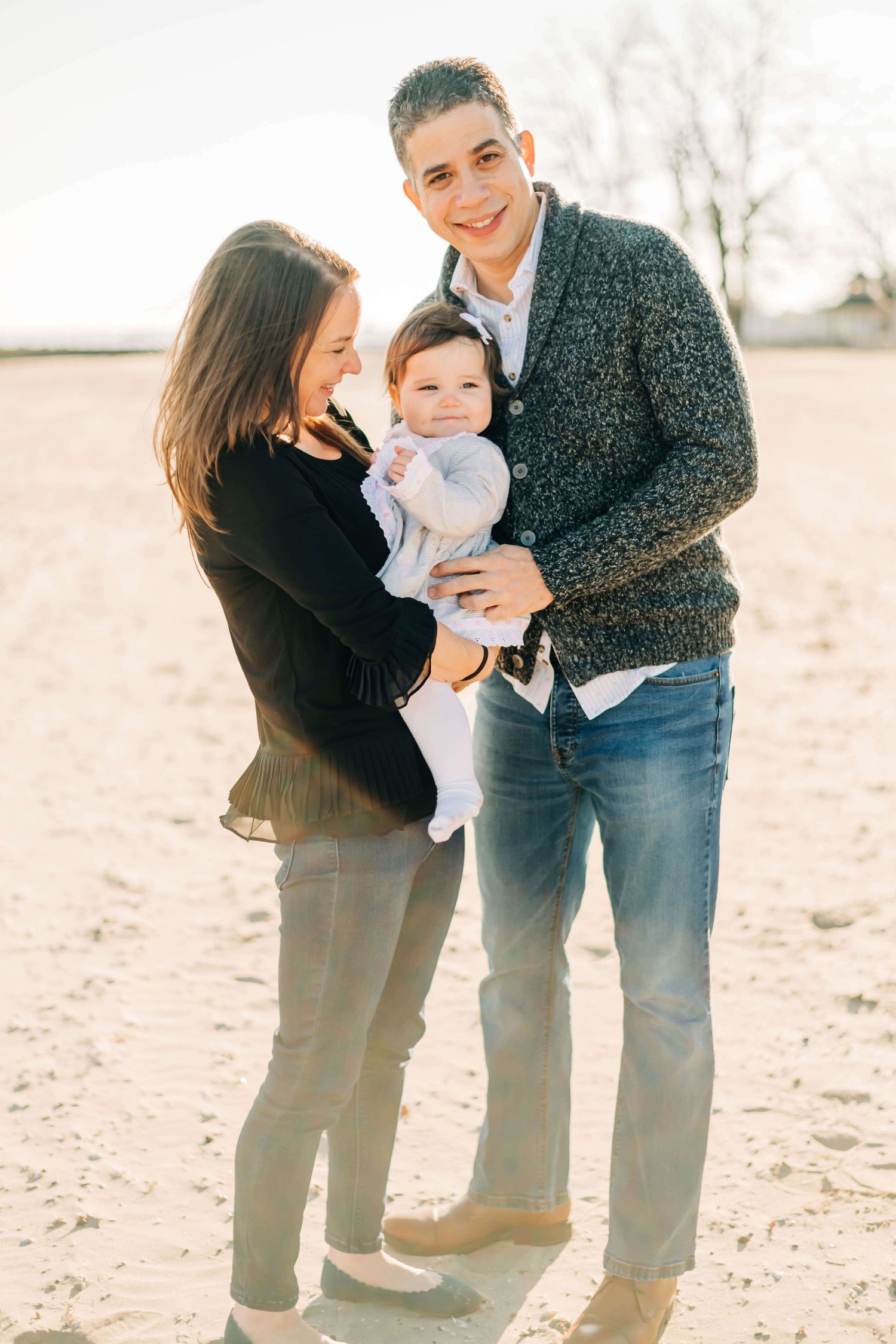 mother and father holding baby girl at a beach