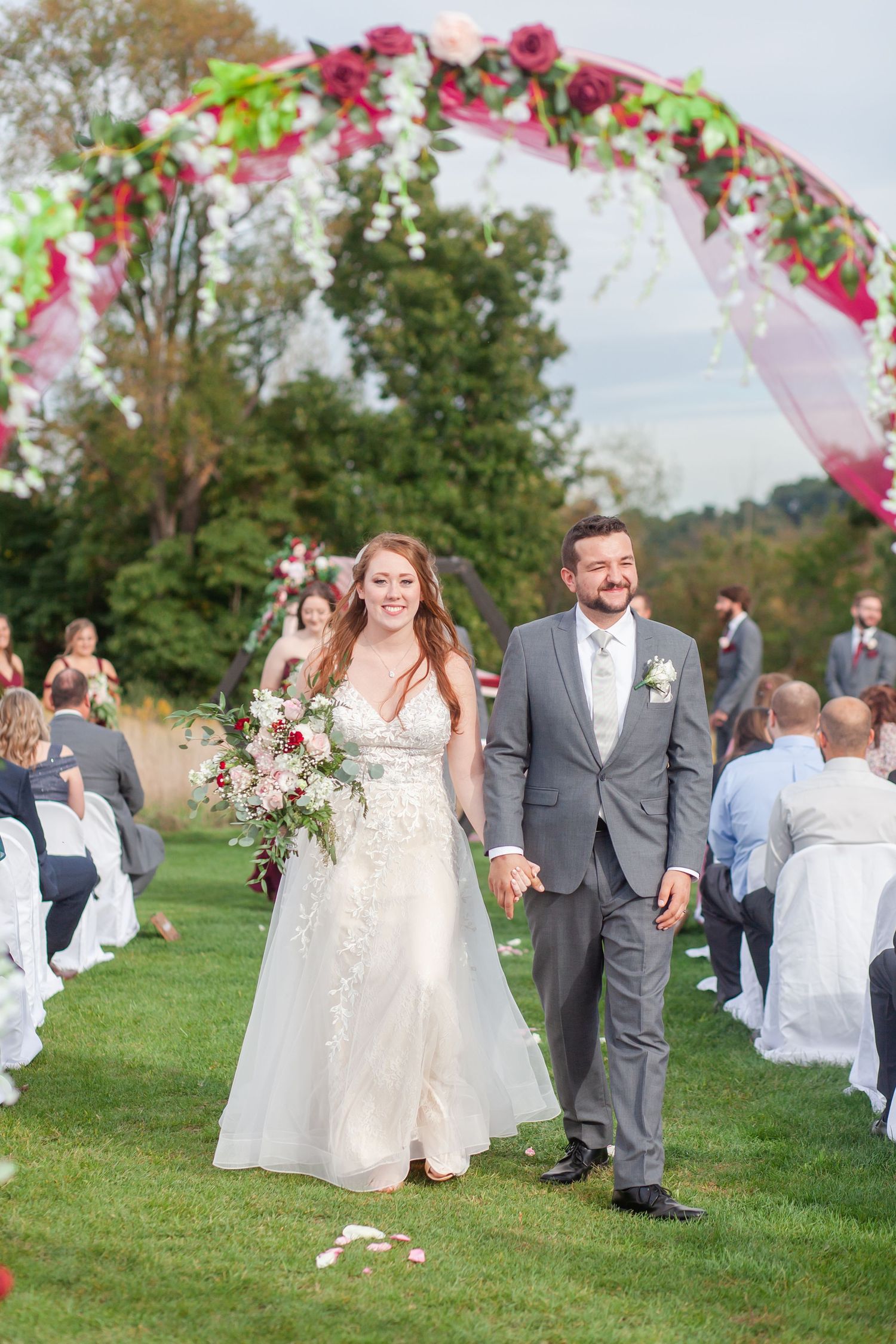 Newlyweds celebrate their special moment under a floral arch with pink and white decorations.