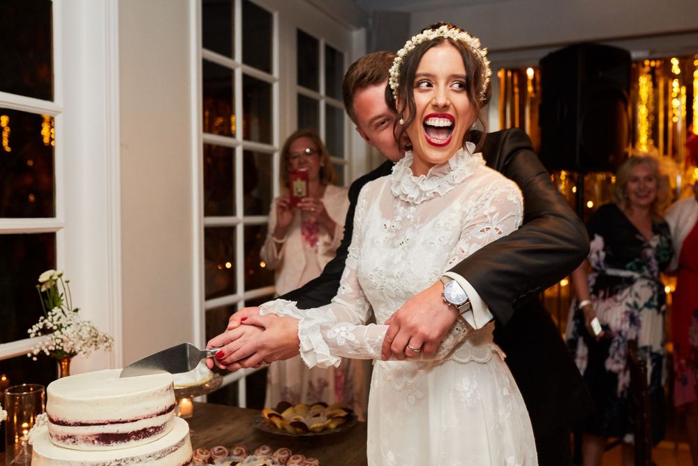Joyful moment during wedding cake cutting with laughter and celebration.