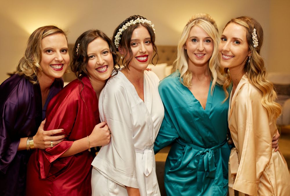 Wedding party wearing colorful silk robes posing together during preparation celebrations.