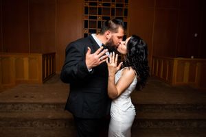 Newlywed couple sharing a romantic first kiss at the altar in a beautifully lit wedding chapel.