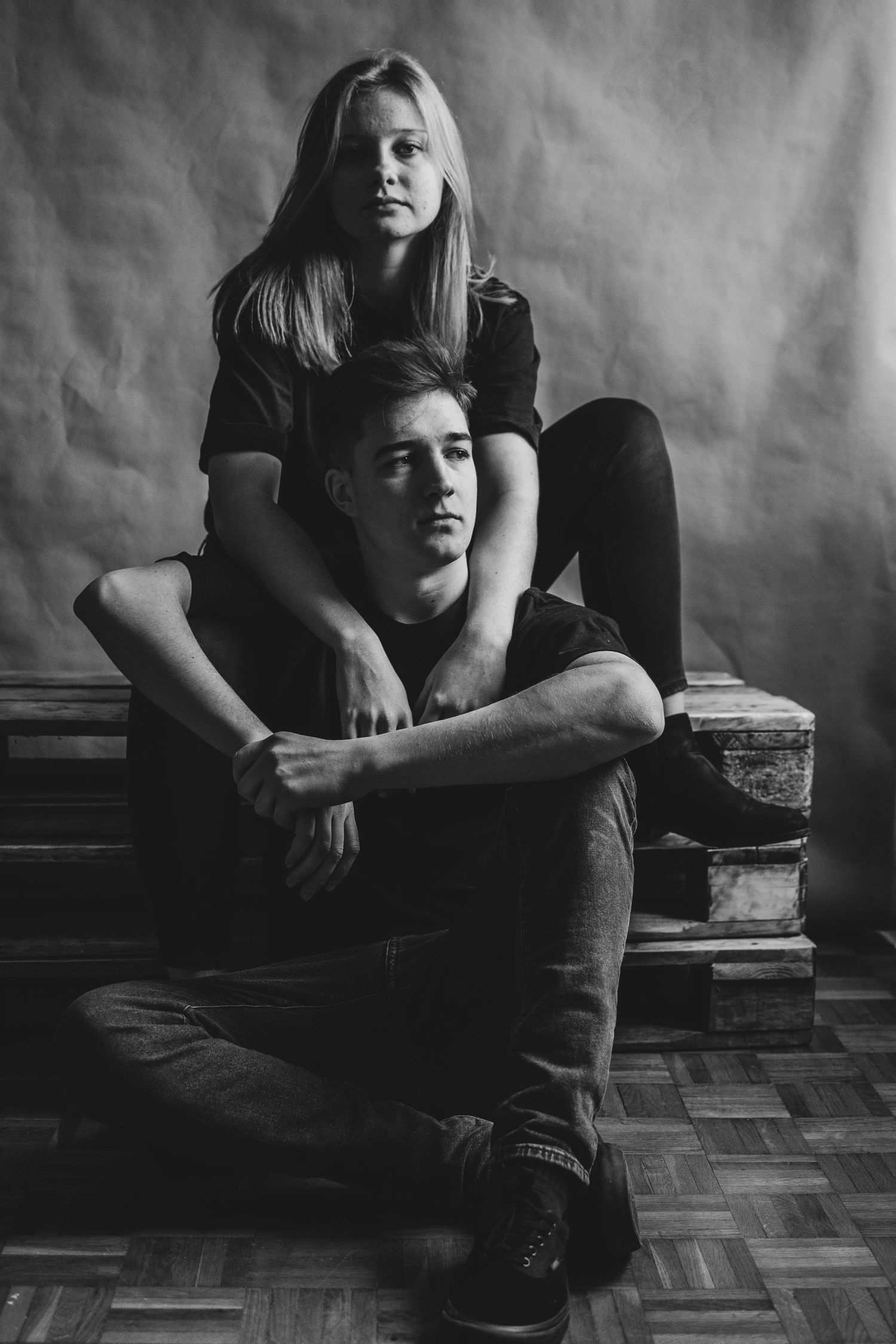 Intimate black and white portrait of two people in casual wear sitting close together.