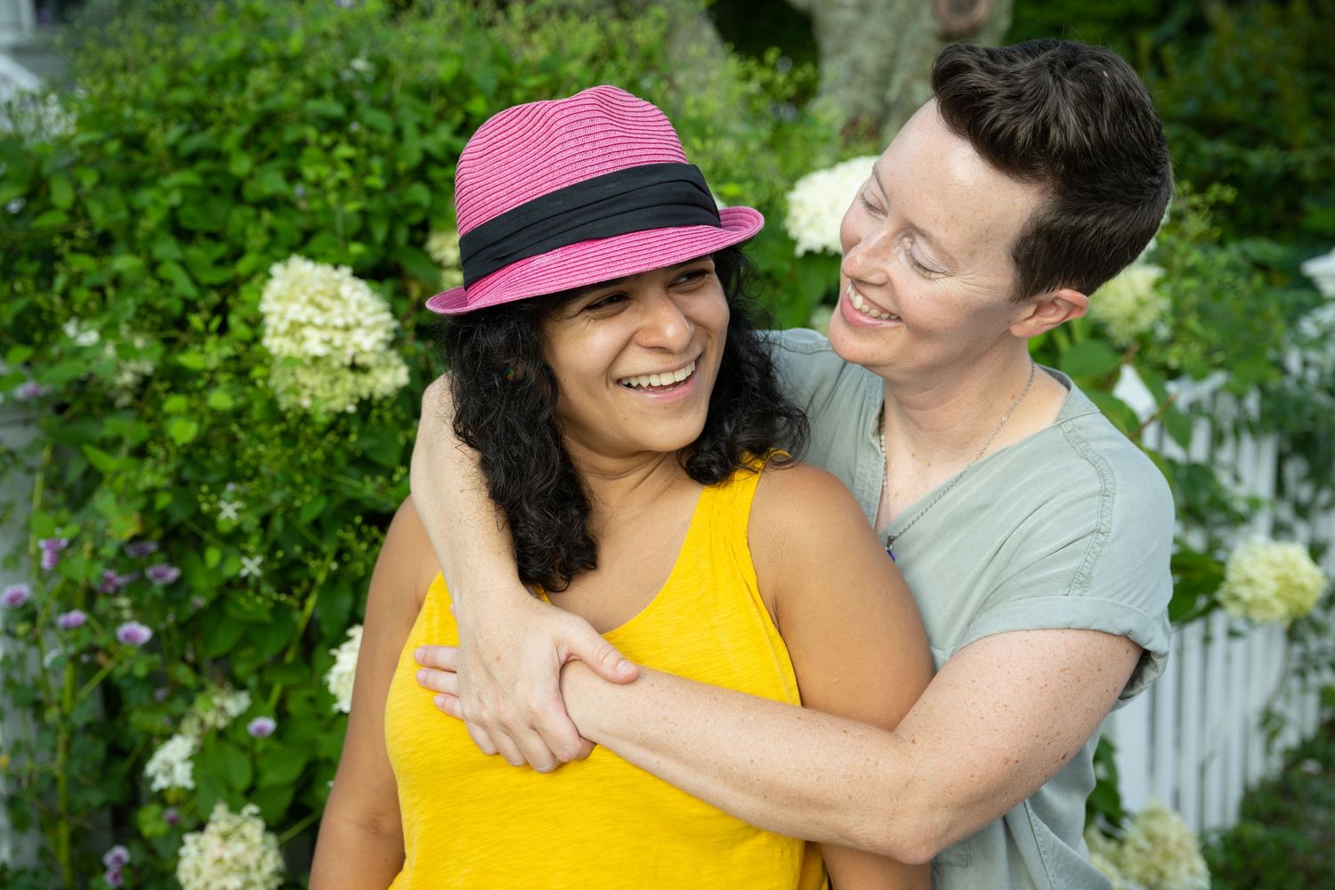 Couple sharing a tender moment in a lush green garden setting on a sunny day.