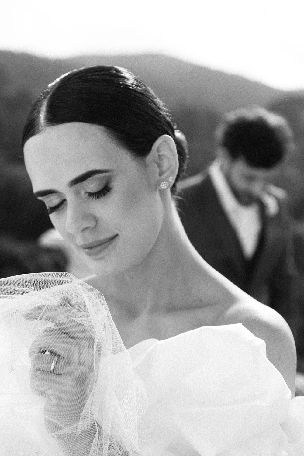 A serene black and white portrait captures a bride in a strapless gown with sleek hair.