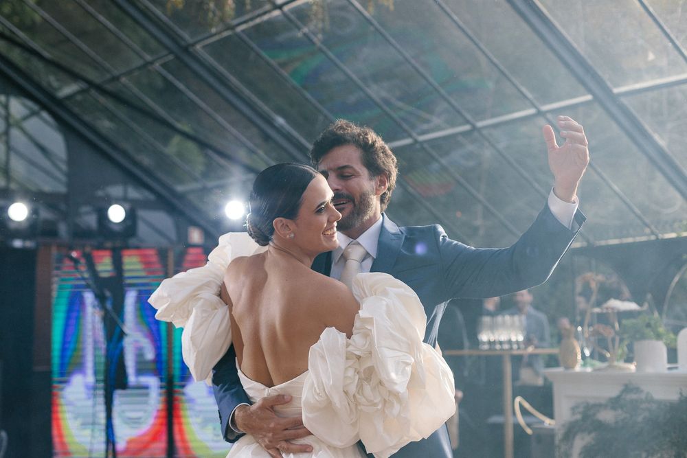 A couple shares their first dance at their wedding reception under atmospheric lighting.