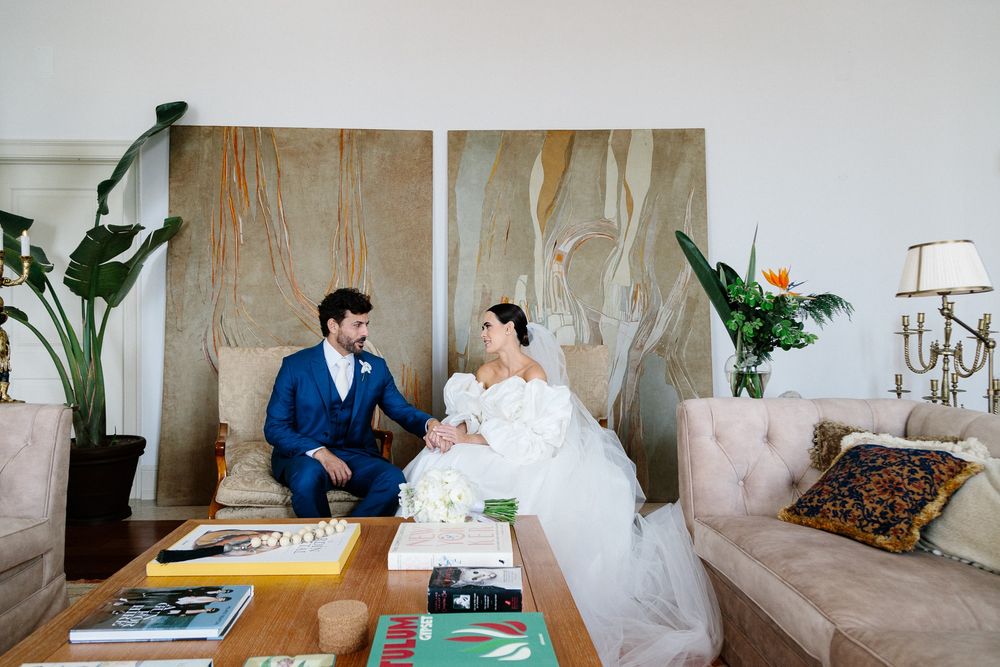 Wedding couple relaxing on elegant furniture with modern abstract art backdrop.