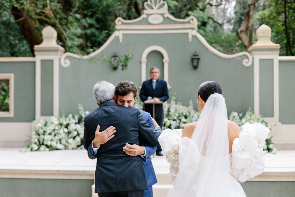 Wedding ceremony taking place at an elegant outdoor venue with ornate grey arch.
