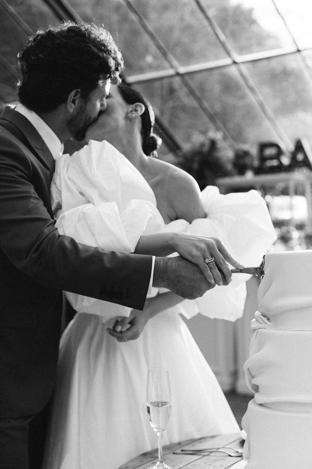 Black and white photo of couple cutting their wedding cake together.