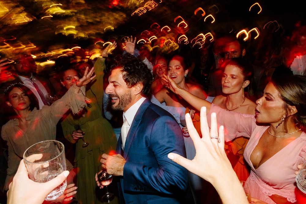 Lively wedding reception party scene with guests dancing under warm lighting and bubbles.