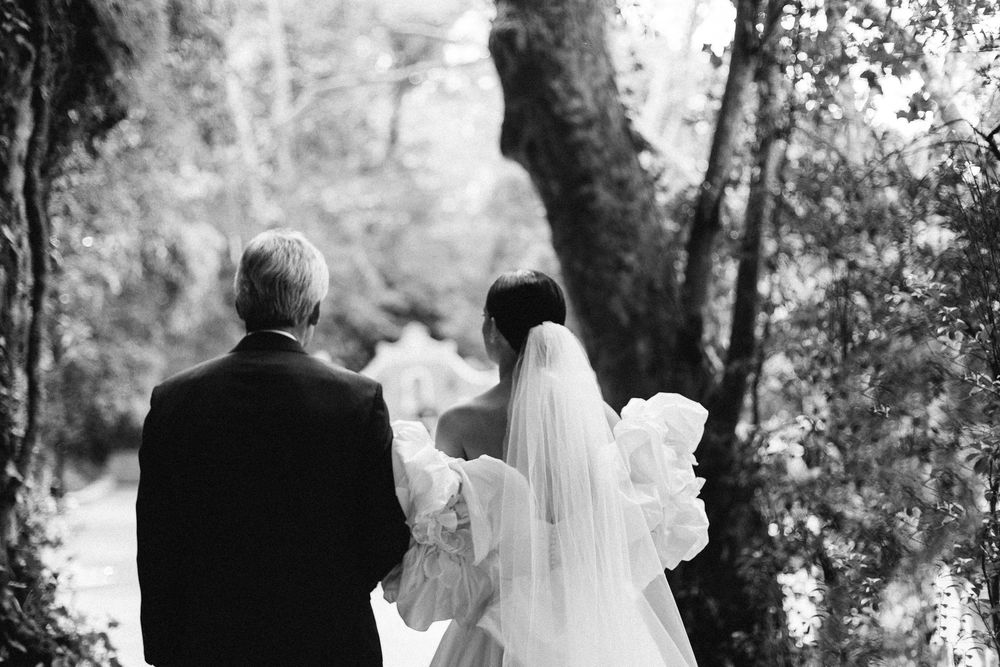 Black and white wedding portrait on woodland path with flowing veil.