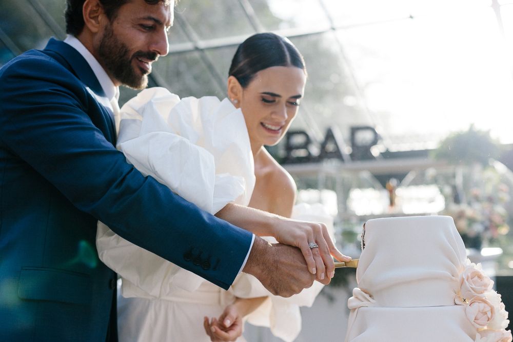 Newlyweds cut their elegant white wedding cake together at their reception.
