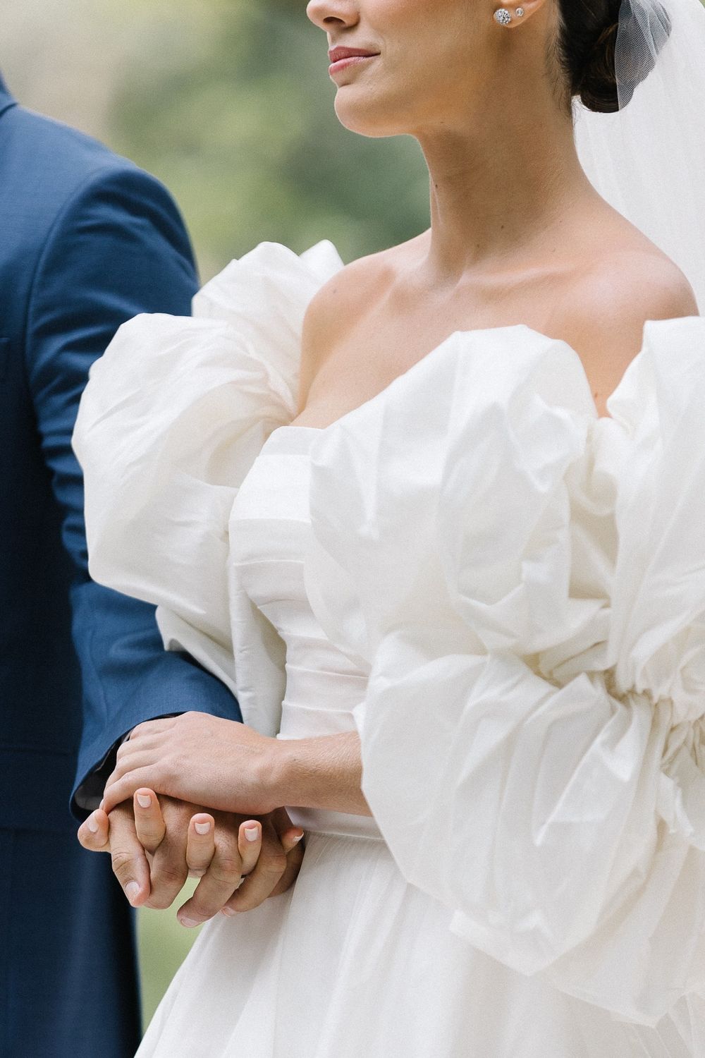 Close-up detail of a bride's white wedding dress with dramatic puff sleeves.