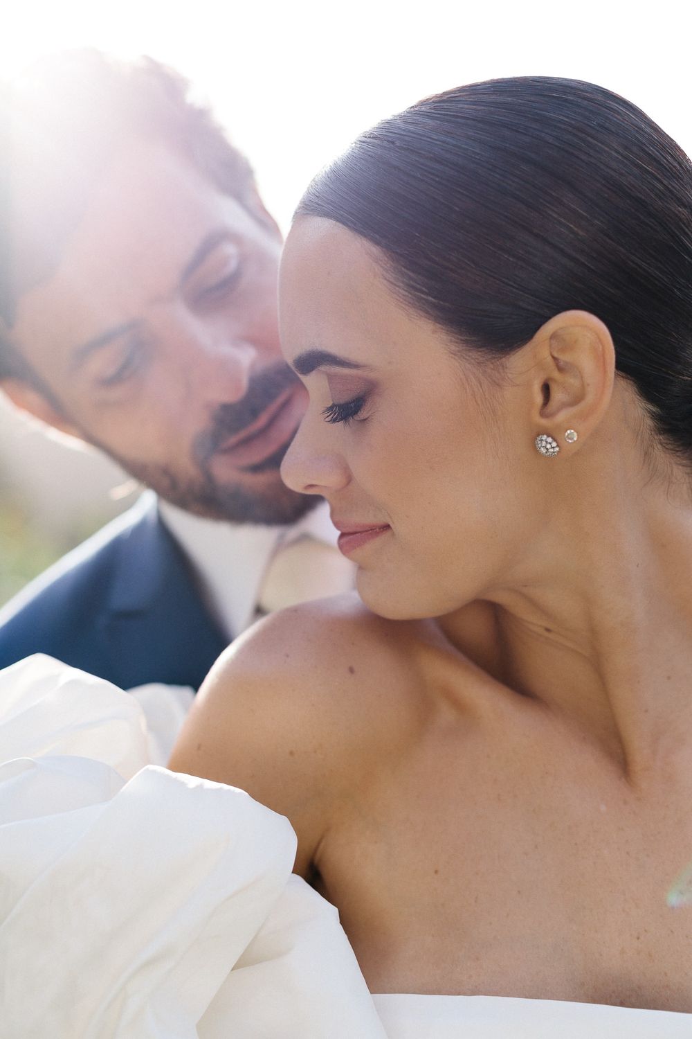 Romantic close-up portrait of newlyweds in soft sunlight.