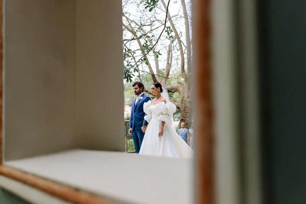 Framed view through window of wedding couple in formal attire outside.