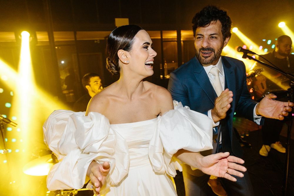 Couple dancing and celebrating at wedding reception with dramatic yellow lighting.
