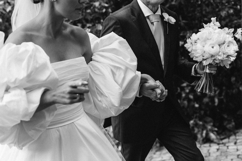 Black and white photo showcasing the dramatic puff sleeves of a strapless wedding gown.