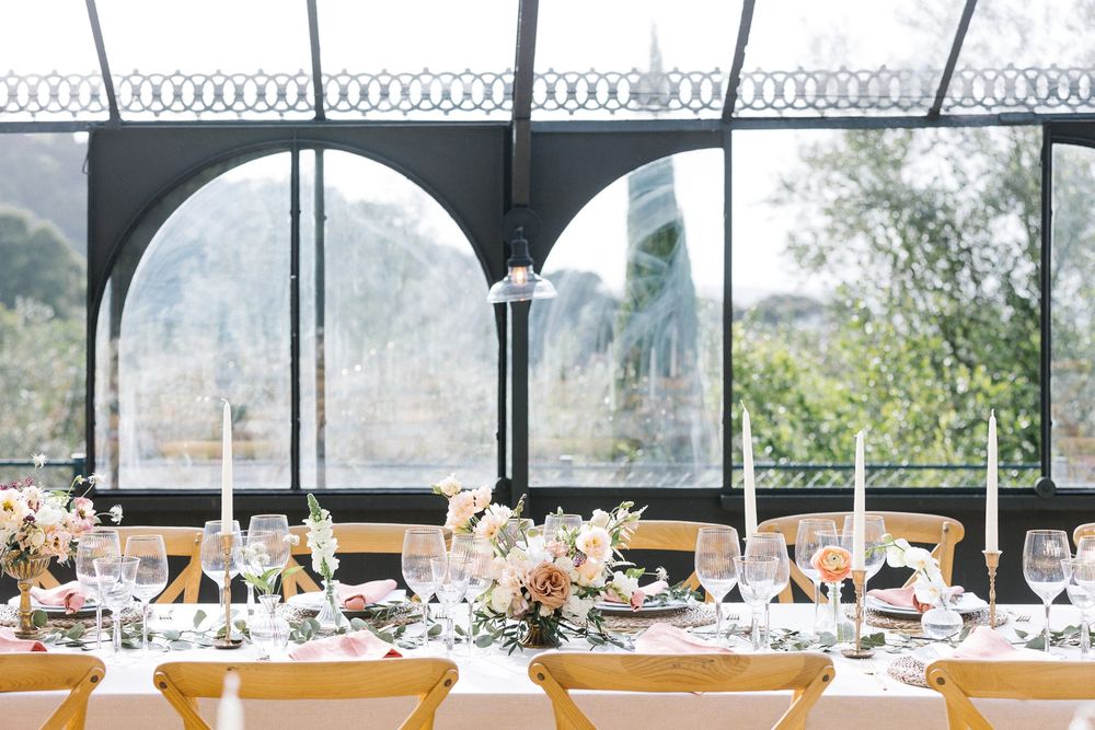 Elegant wedding reception setup under arched windows with natural light streaming in.