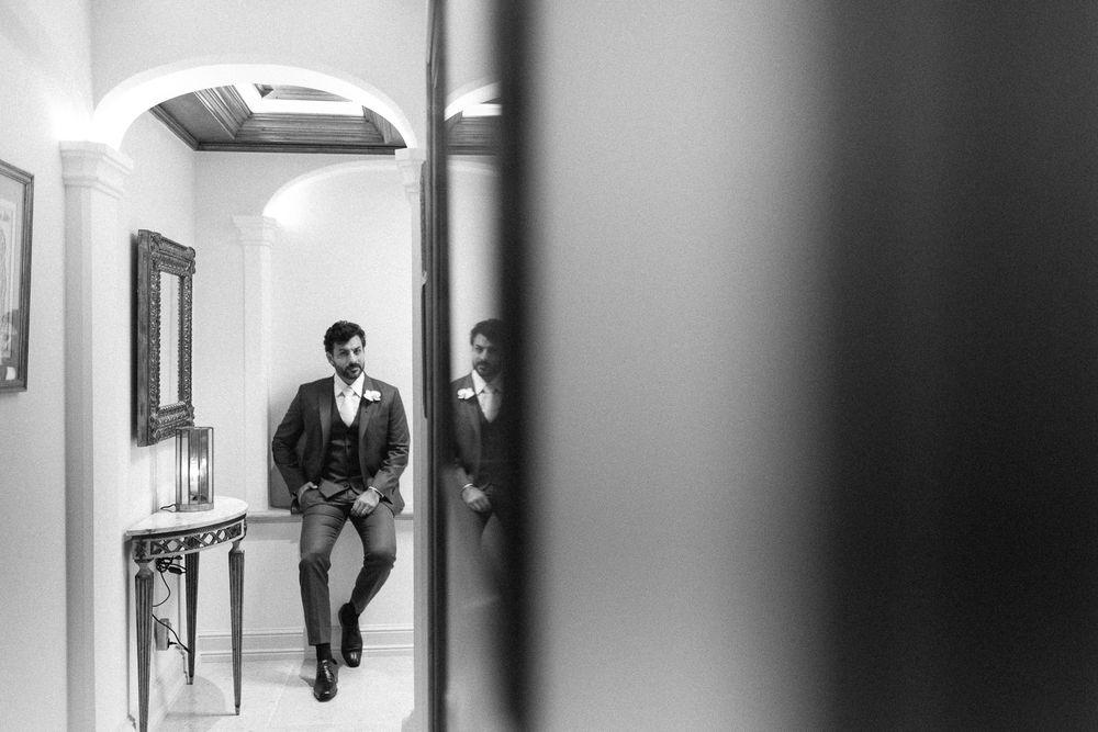 Artistic black and white shot of a groom waiting in a hallway before the ceremony.