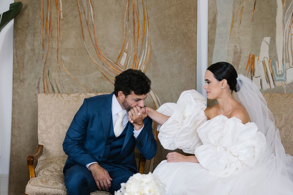 Tender moment between newlyweds on a beige sofa with abstract wall art behind them.