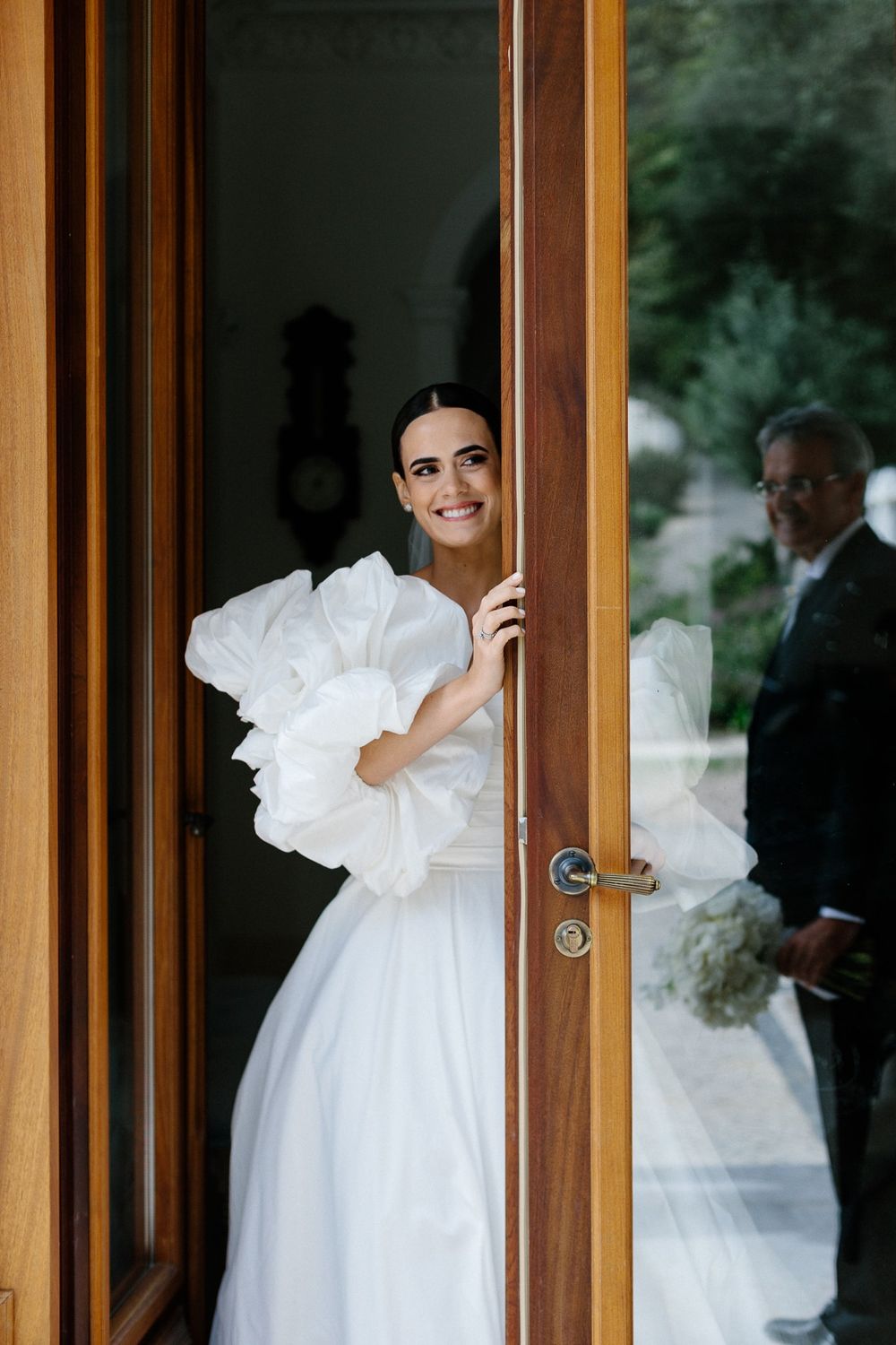 Joyful candid moment through wooden doorway on wedding day.