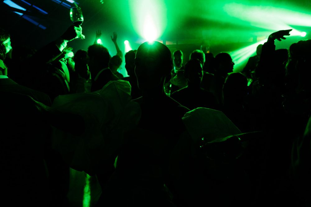 Dance party silhouettes illuminated by green stage lighting.