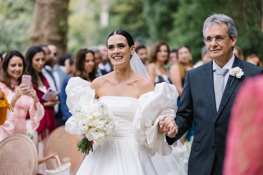 Wedding ceremony outdoors with guests watching the bride walking down the aisle.