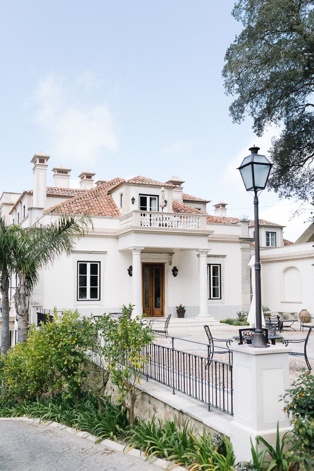 Mediterranean-style white villa with terracotta roof and elegant front porch.