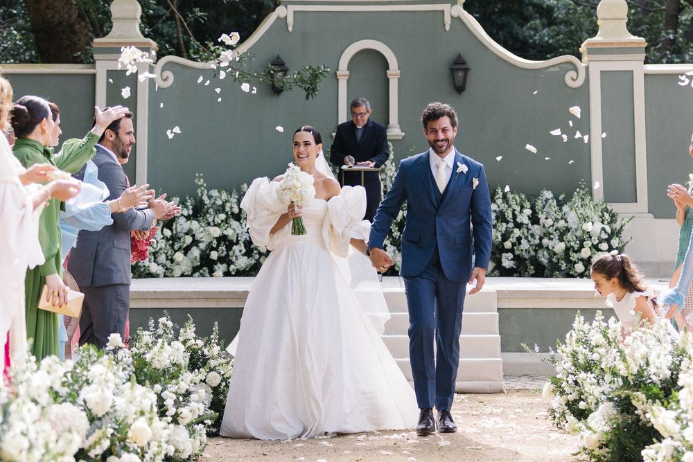 A joyous wedding celebration with white floral decorations and guests throwing petals in celebration.