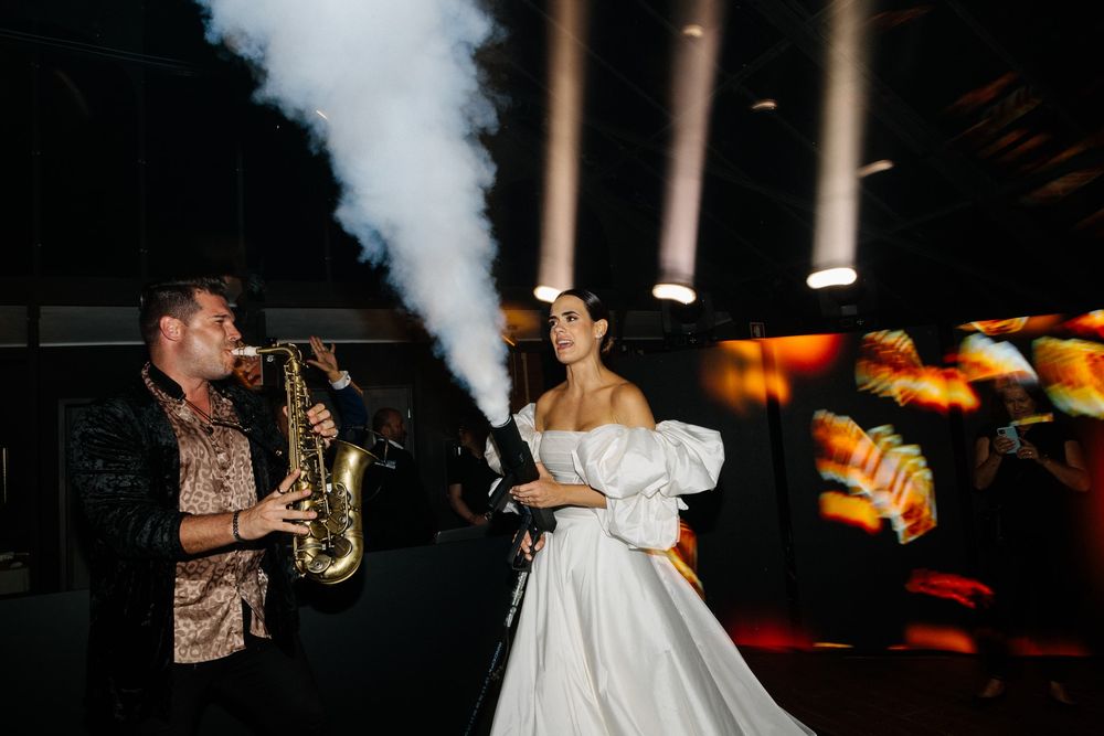 A saxophonist performs while a dancer in white twirls on the dance floor.