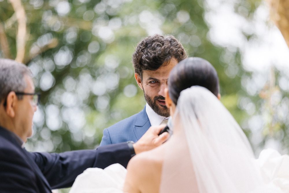 Intimate moment during outdoor wedding ceremony with bride in white gown.