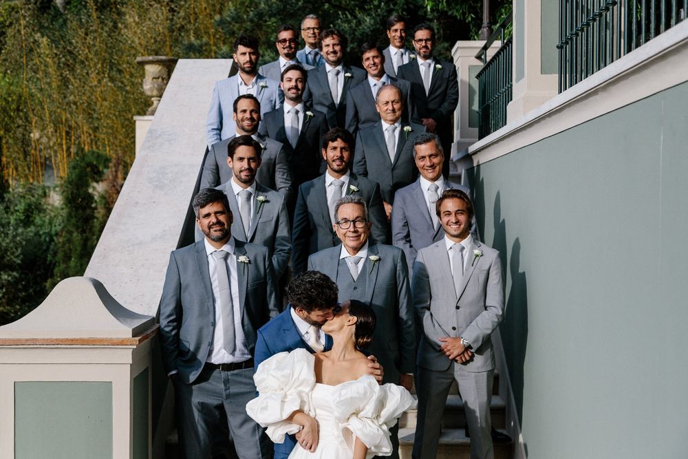 Wedding party poses for formal group photo on elegant white stone staircase.