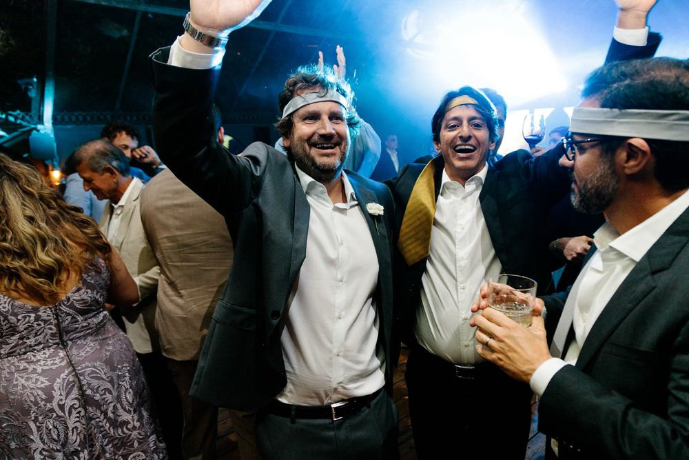 Wedding guests celebrating joyfully on dance floor during reception.