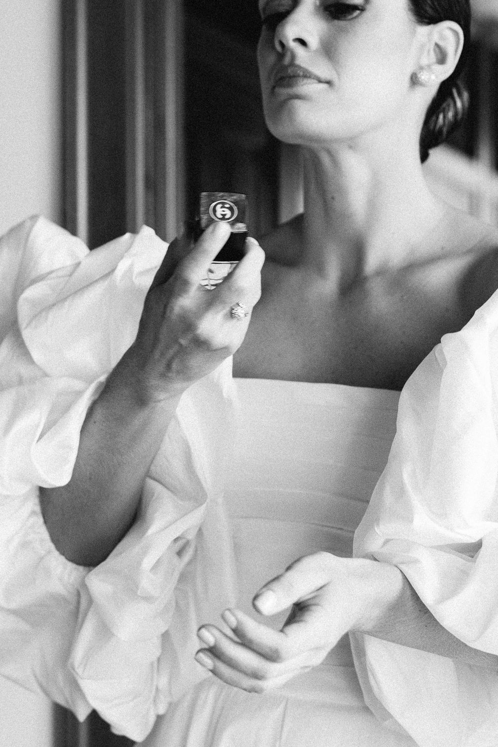 Black and white photo of someone in white holding and examining a small box or ring.