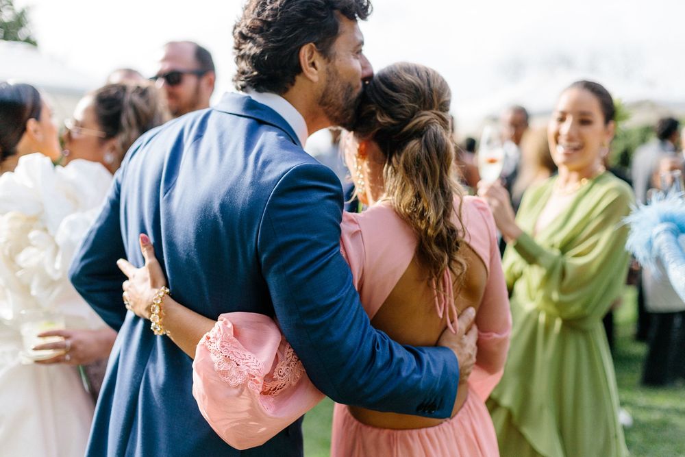 Wedding reception guests dancing and embracing outdoors in colorful attire.