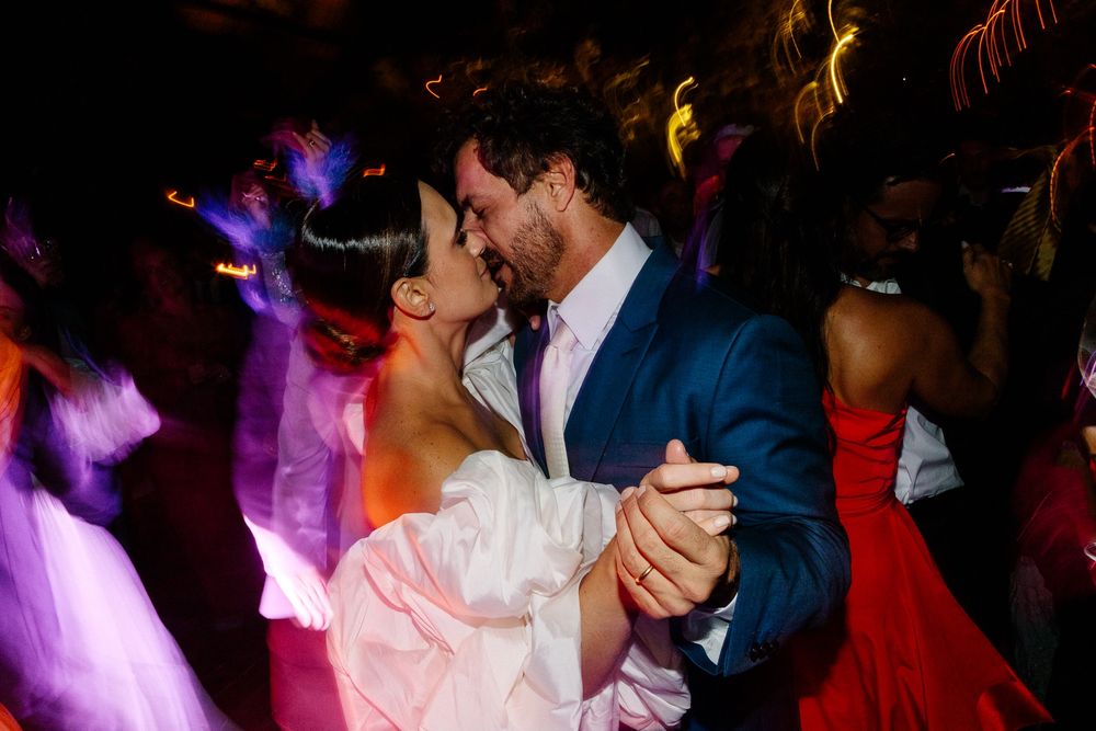 A couple dances together at their wedding reception under colorful lighting.