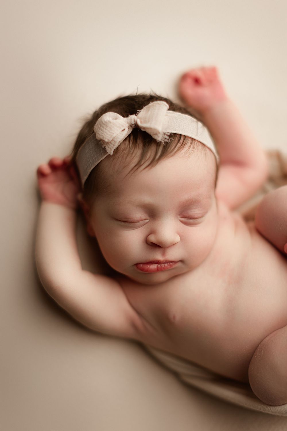 baby girl with a blush pink bow sleeping on back for her newborn session