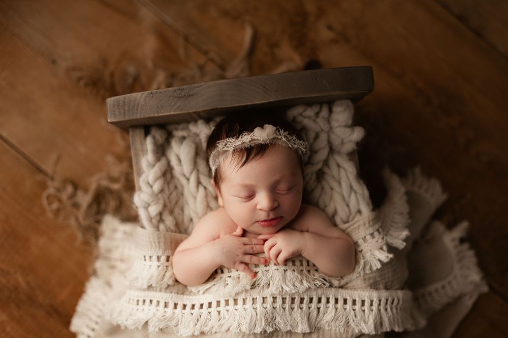 baby girl posed in a wooden prop crib sleeping