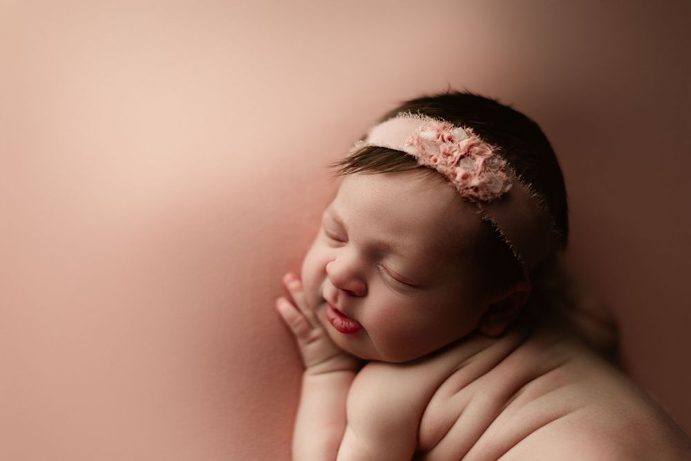newborn girl on pink backdrop side laying pose newborn photography
