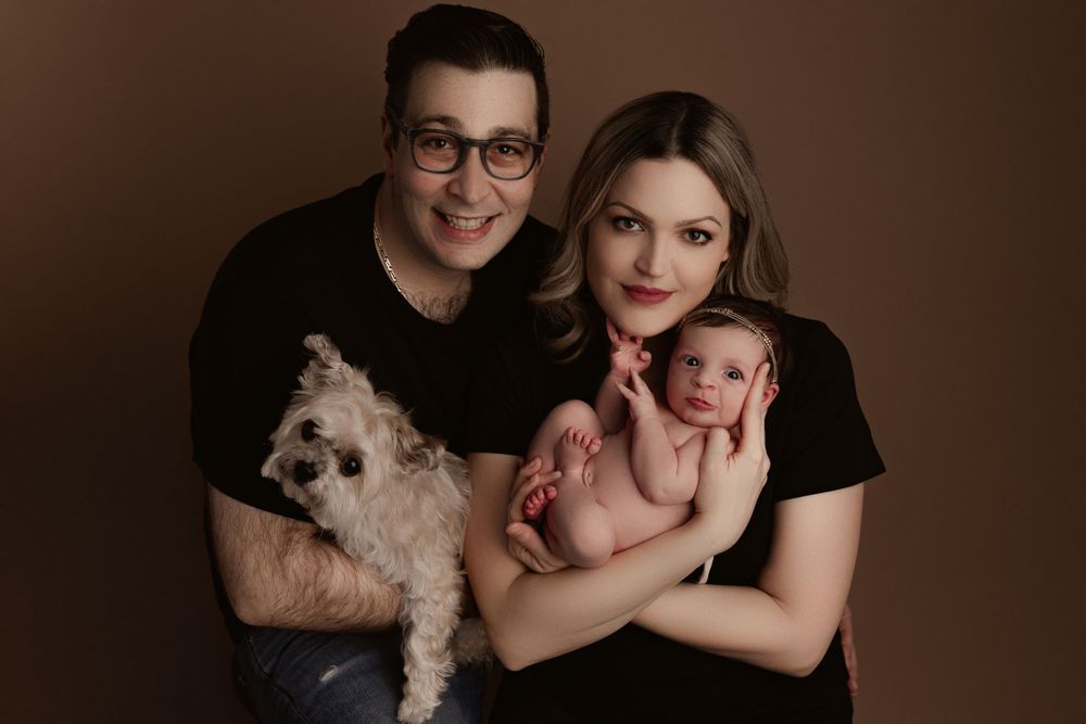 mom, dad, newborn baby girl and their dog posed for a family photo