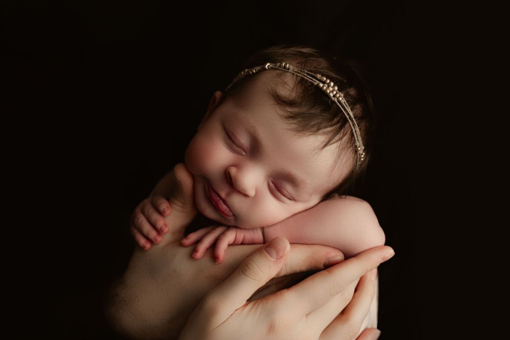 newborn baby girl in her daddy's hands smiling