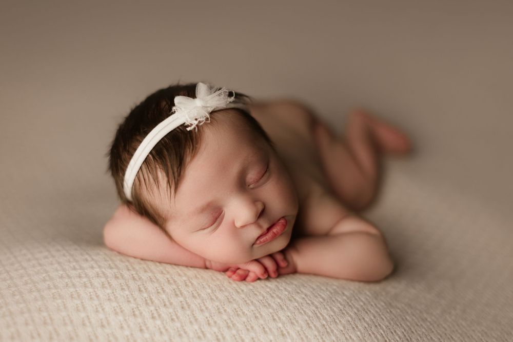 newborn girl on white backdrop for newborn session forward facing pose