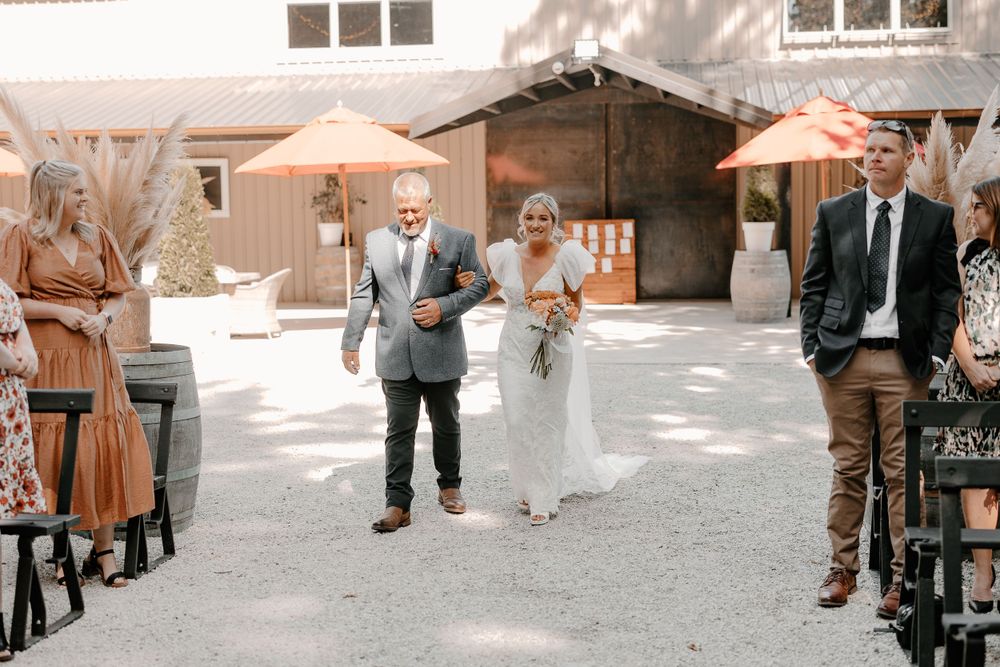 Wedding guests walking along outdoor venue pathway.