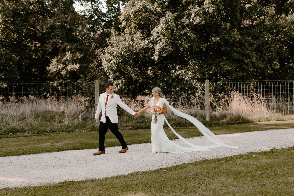 Wedding couple walking hand in hand through a scenic outdoor path.