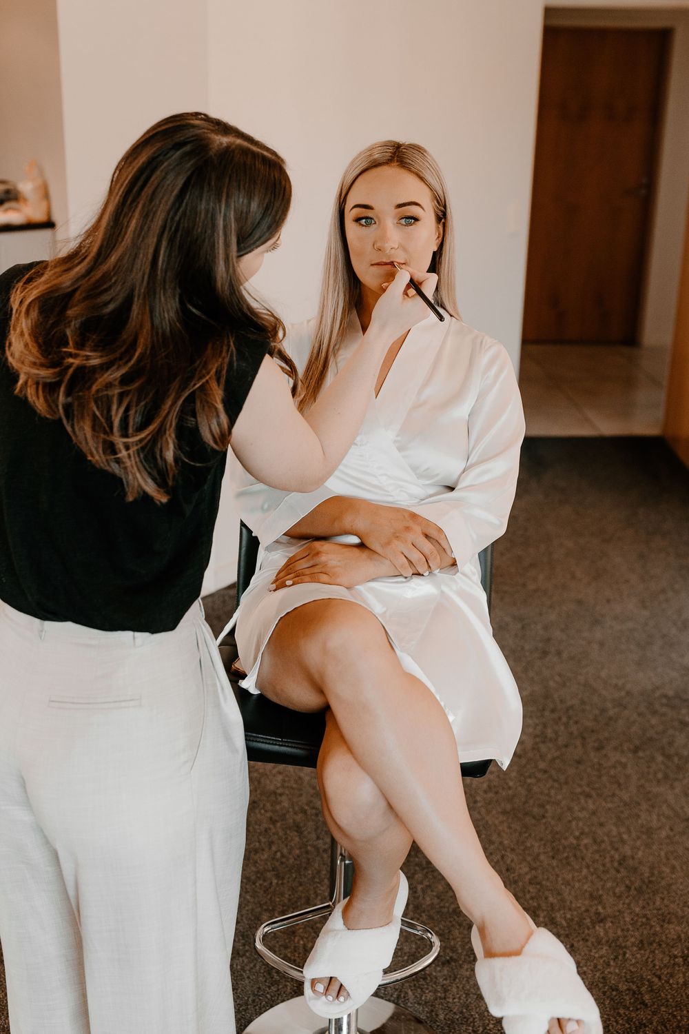 Behind-the-scenes of bridal preparation with makeup application in white robe.