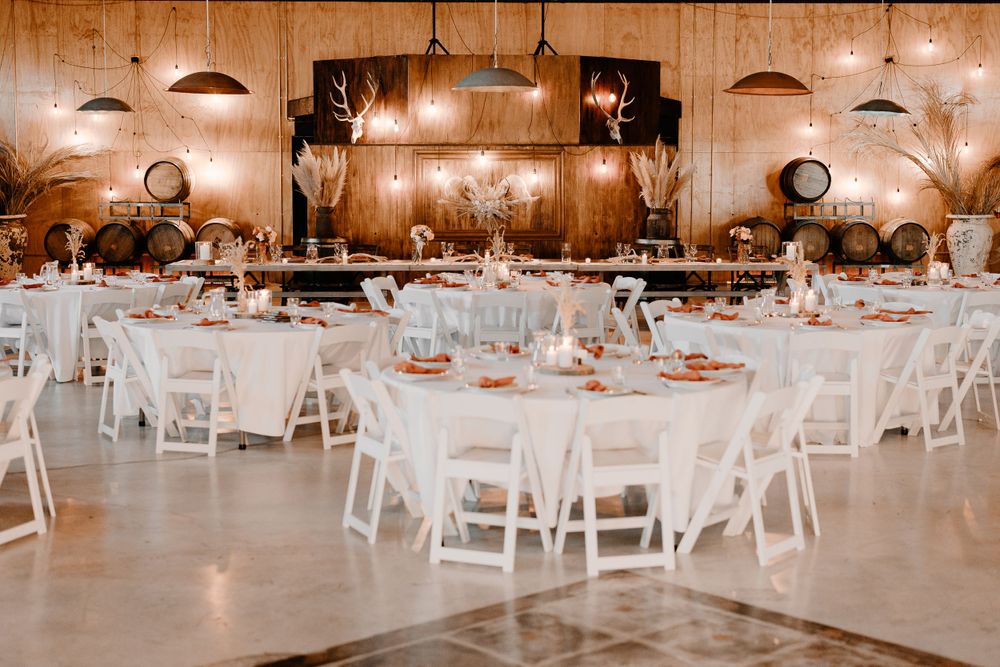 Rustic barn wedding reception venue with white chairs and warm lighting.