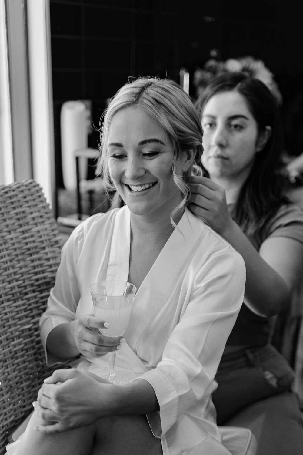 Black and white candid moment of bridal preparation with hair styling.