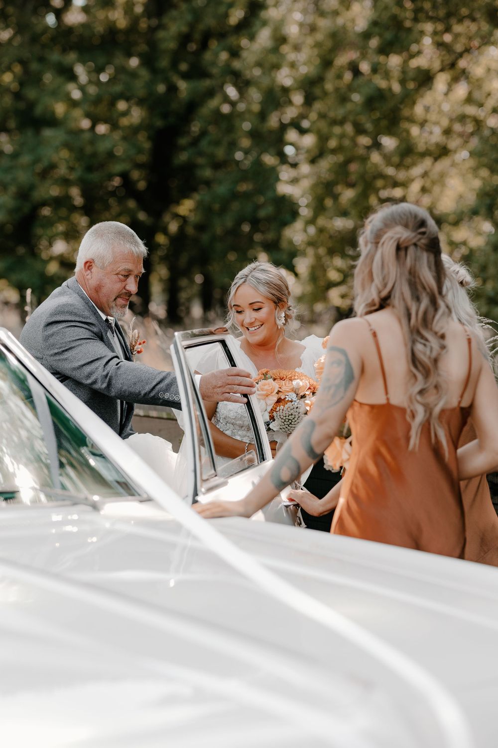Wedding party gathered at rustic outdoor reception venue with white decor.